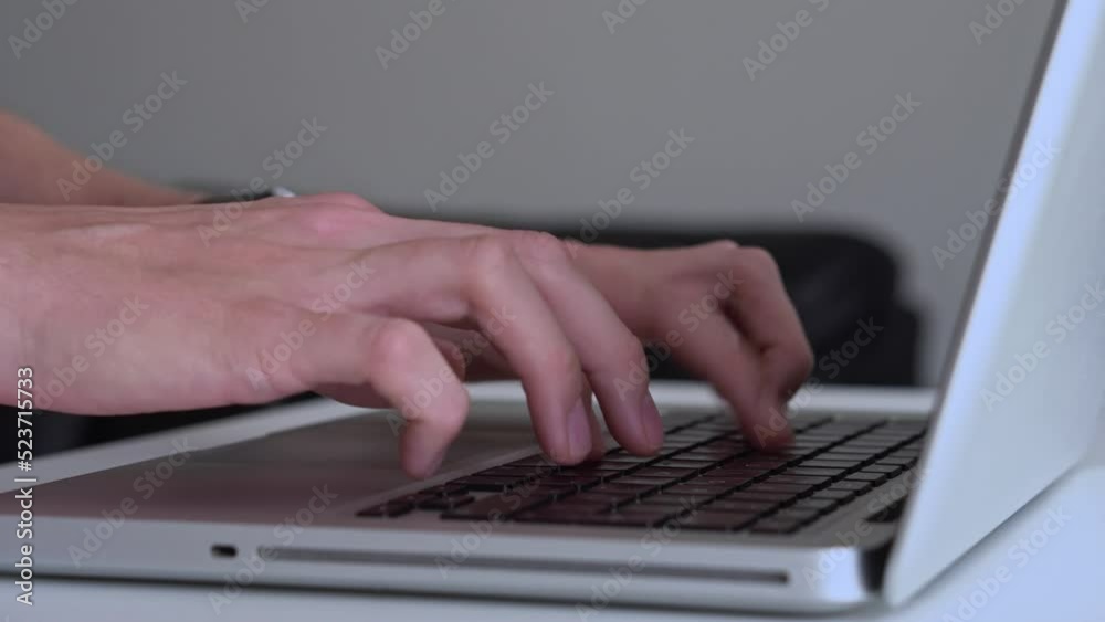 Close-up of male hands typing on laptop. Side view
