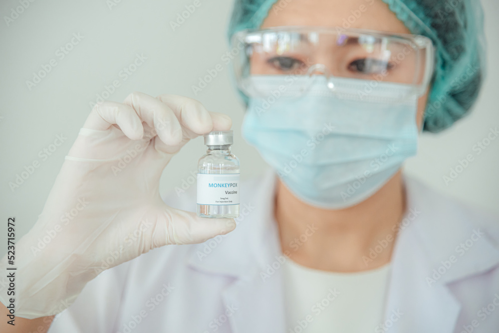 A doctor or scientist is holding a vaccine vial for monkeypox or clade. A doctor or scientist is holding a vaccine vial for monkeypox or clade.
