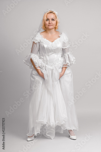 bride in holding on to the hem of a wedding dress on a white background. full height © Sergey