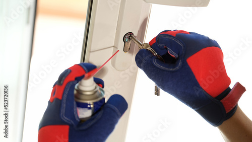 Repairman using lubricate in spray can for lock of plastic window