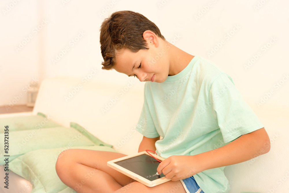Happy caucasian boy writing in a blackboard with smile sitting outdoors. Happy caucasian boy writing in a blackboard with smile sitting outdoors.