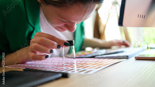 Female graphic designer looking at colors samples through magnifying glass