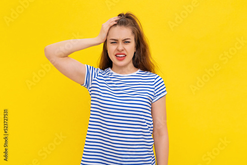 Shocked young woman forgot, remember smth, slap forehead and gasping startled, realize something, standing in white-blue striped t shirt over yellow background