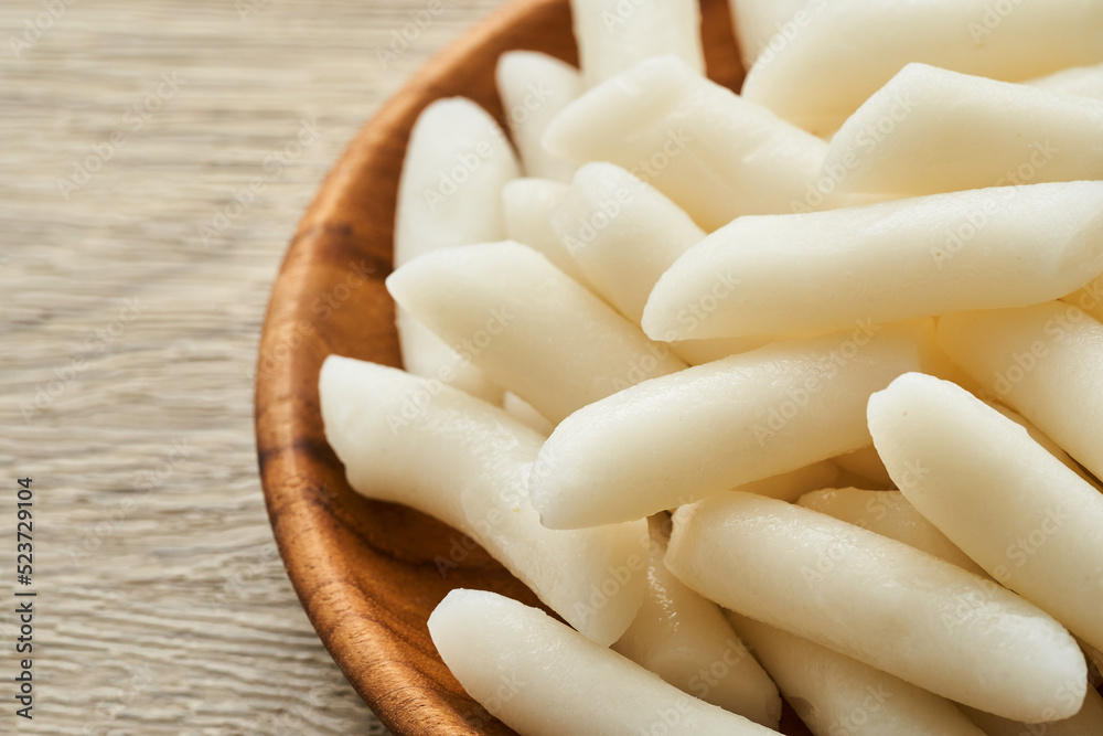Tteok or Korean Rice Cakes in a wooden plate on wood table background Tteok or Korean Rice Cakes in a wooden plate on wood table background