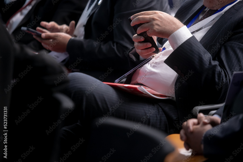 Audience in the conference hall. The man in the foreground looking into your phone