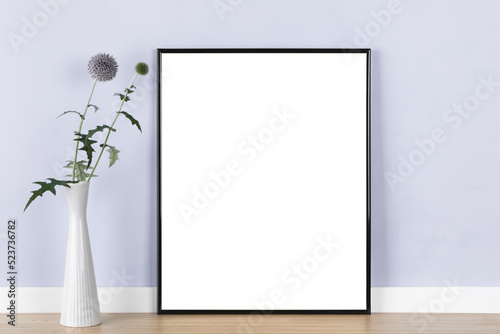 Poster artwork mockup template with transaprent black picture frame and globe thistle in vase in front of pastel purple wall © eyewave