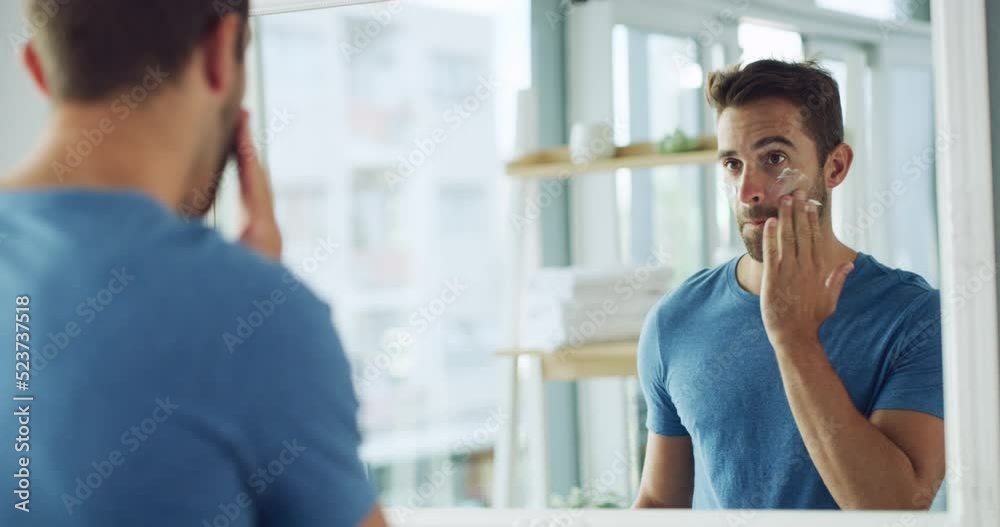 Man applying face cream for skincare, hygiene and grooming during morning routine in bathroom at home. Fresh, flawless and handsome male keeping skin clear, smooth and soft with sunscreen and lotion
