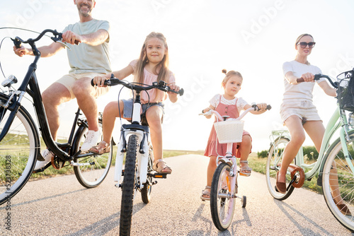 Family of four caucasian people sitting on bikes on village road