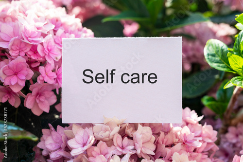 Self-care word on lightbox and flower narcissus on pink background flat lay. Take care of yourself
