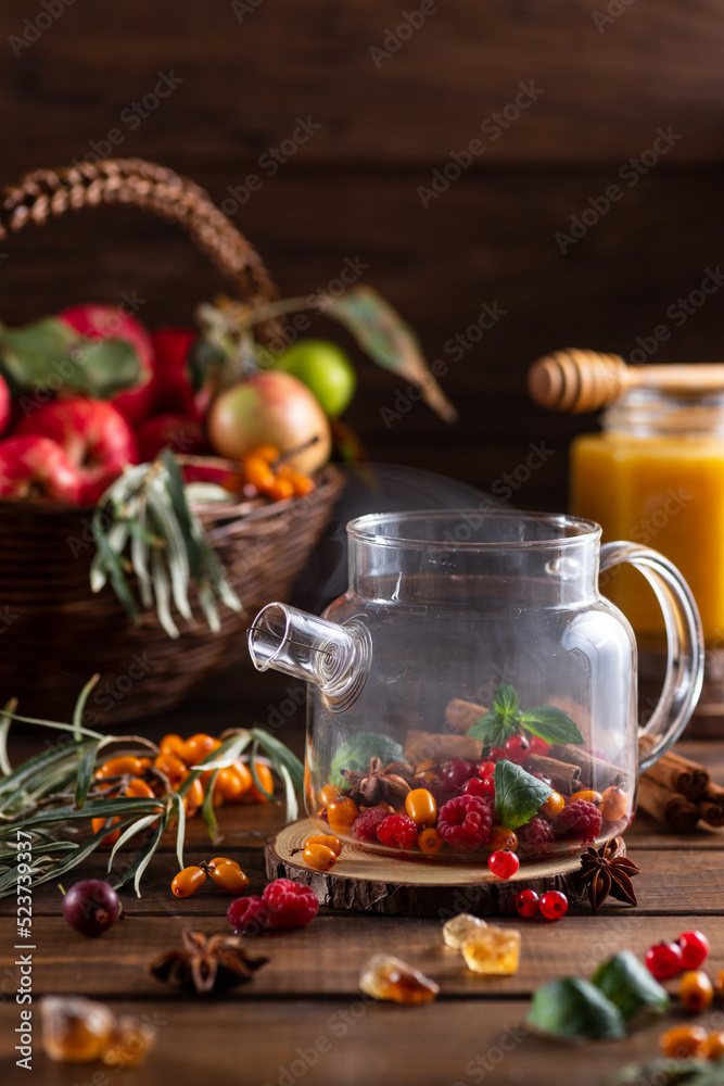 Berry tea. Sea buckthorn and raspberries in a glass teapot, cups with poured tea