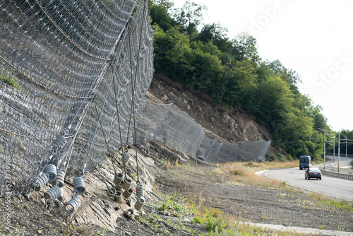 Active robust rockfall barrier system with wire mesh along the road, brake for rocks fall. Slope strengthening after landslide in Tskneti Georgia.  photo