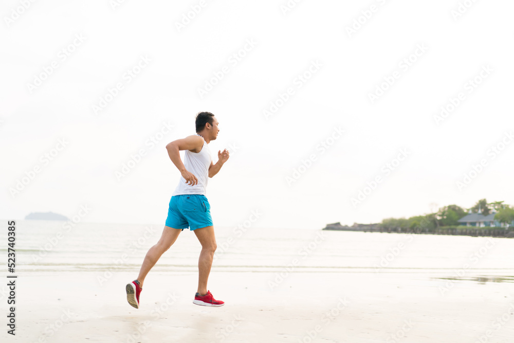 asian sport man running along seaside. running on beach with healthy toned legs body, Hamstring muscles, knee joint health active lifestyle panoramic banner background. the beach runners working out asian sport man running along seaside. running on beach with healthy toned legs body, Hamstring muscles, knee joint health active lifestyle panoramic banner background. the beach runners working out