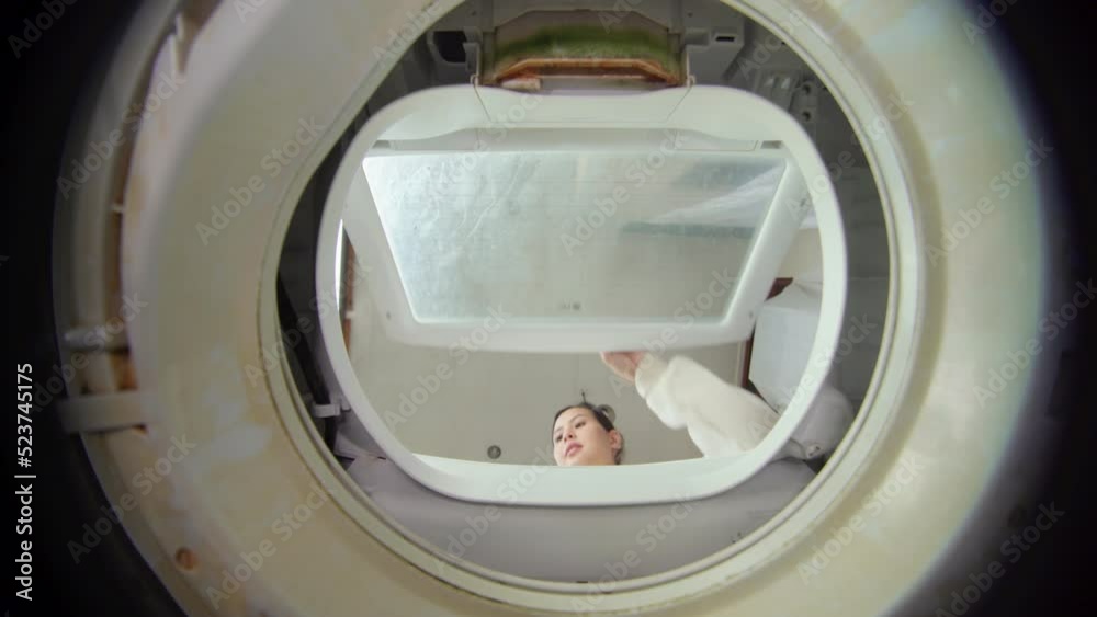 Woman Opens The Lid And Looking Inside The Washing Machine . - low angle Woman Opens The Lid And Looking Inside The Washing Machine . - low angle