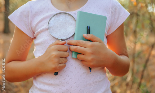 Fotografia close up of children hands naturalist botanist with magnifying glass and noteboo