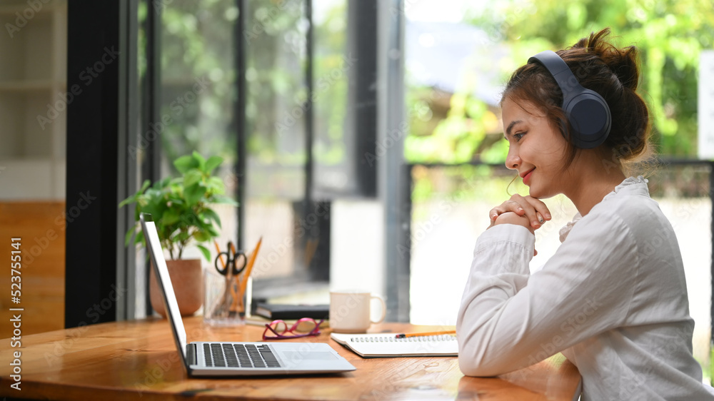 Young businesswoman making video call to business partner or watching online webinar on her laptop