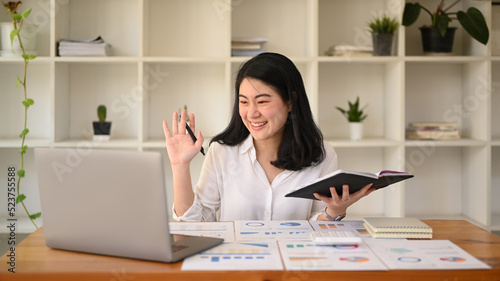 Young businesswoman making video call to business partner or watching online webinar on her laptop