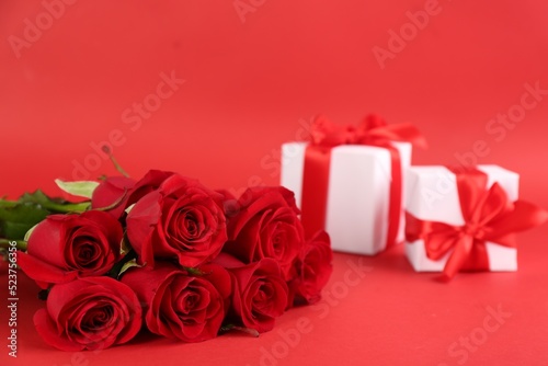 Beautiful roses and gift boxes on red background  space for text. St. Valentine s day celebration