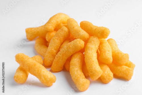 Heap of tasty cheesy corn puffs on white background, closeup