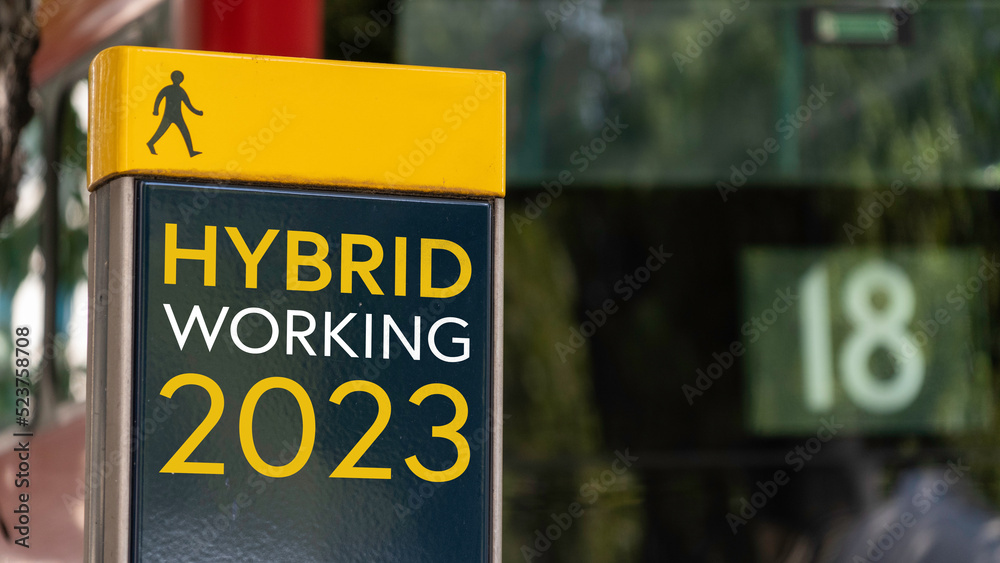 Hybrid working 2023 sign in a busy commuter city center Hybrid working 2023 sign in a busy commuter city center
