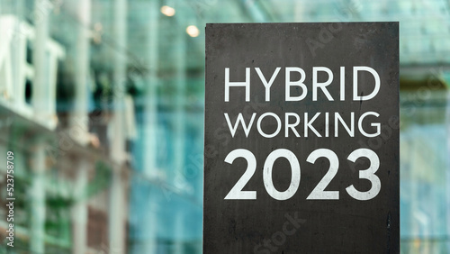 Hybrid working 2023 on a sign outside a modern glass office building 