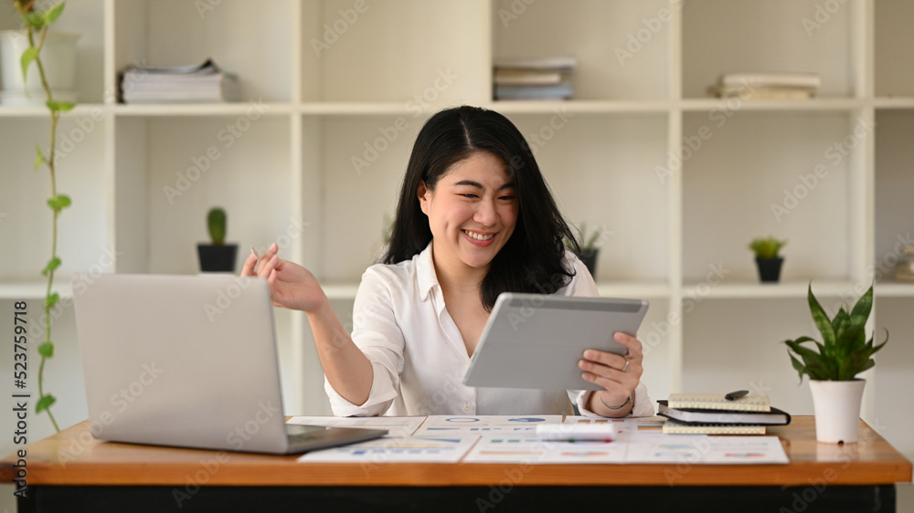 Young businesswoman using laptop and working with financial document at contemporary workplace Young businesswoman using laptop and working with financial document at contemporary workplace