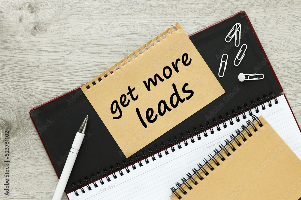 Get More Leads. torn sheet from notepad on planner with text on wooden table