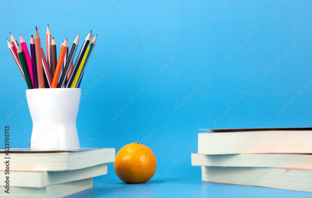 A back to school concept design with Composition with different school stationery on wooden table against light blue background. Back to school.j
