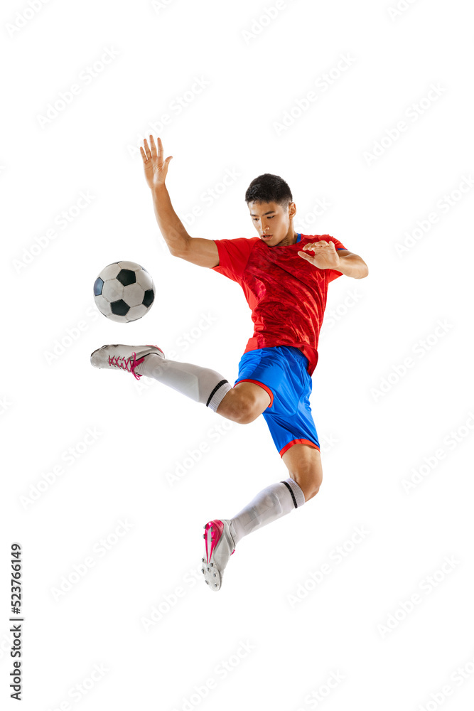 Portrait of young man, football player in motion, training, kicking ball in a jump isolated over white studio background