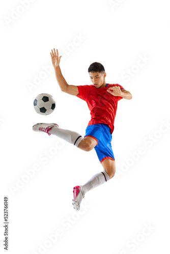 Portrait of young man, football player in motion, training, kicking ball in a jump isolated over white studio background
