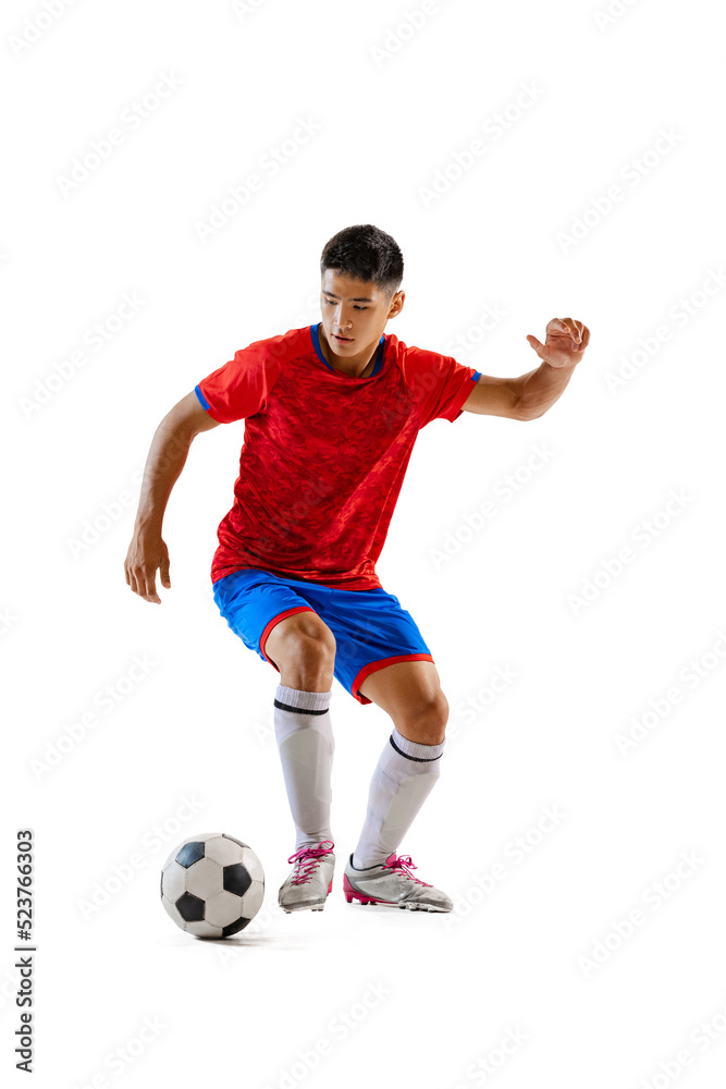 Portrait of young man, professional football player in motion, dribbling, training isolated over white studio background