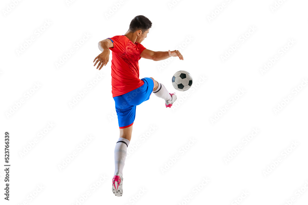 Dynamic portrait of young man, football player in motion, kicking ball isolated over white studio background. Forward position