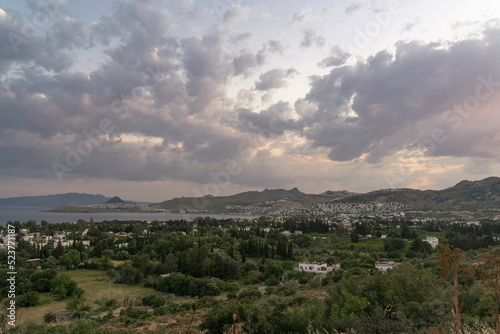 Sunset landscape at Bodrum, Turkey with green trees and sea at cloudy sky. Famous holiday village in Aegean Sea. 