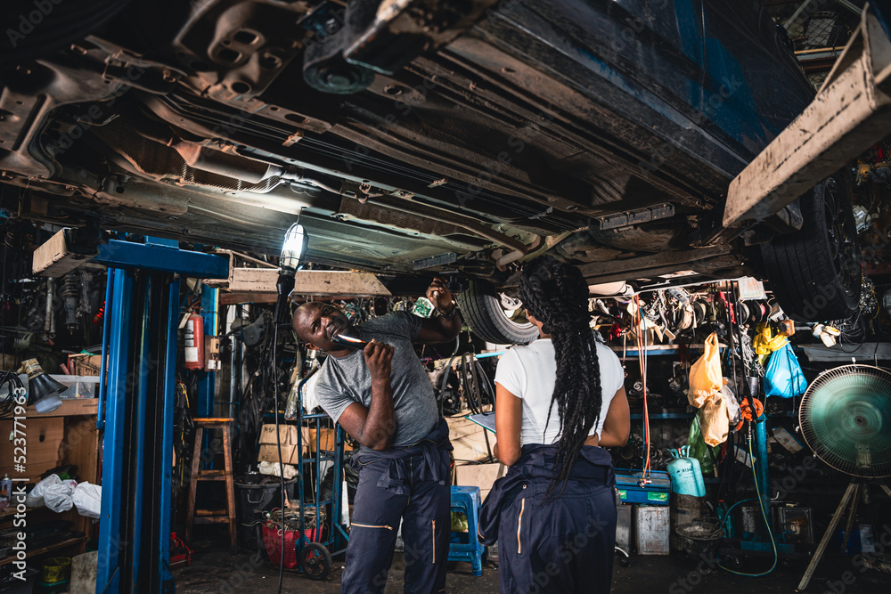 Two mechanic was checking the car suspension. Two mechanic was checking the car suspension.