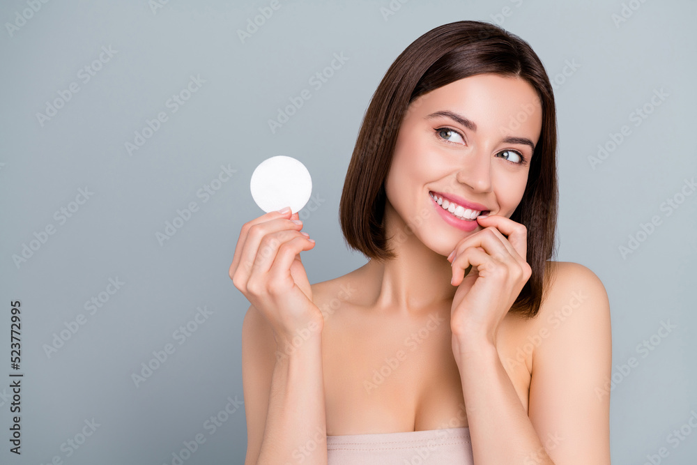 Photo of dreamy lady hold cotton swab imagine remove party make-up tonic isolated over grey color background Photo of dreamy lady hold cotton swab imagine remove party make-up tonic isolated over grey color background