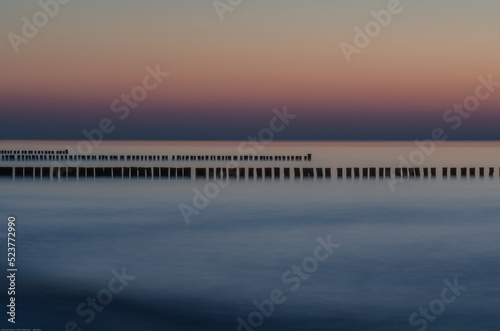Fototapeta Naklejka Na Ścianę i Meble -  Sonnenuntergang an der Ostsee mit Buhnen als Küstenschutz. Buhnen werden auch als Kribbe, Stack, Schlenge oder Höft bezeichnet.