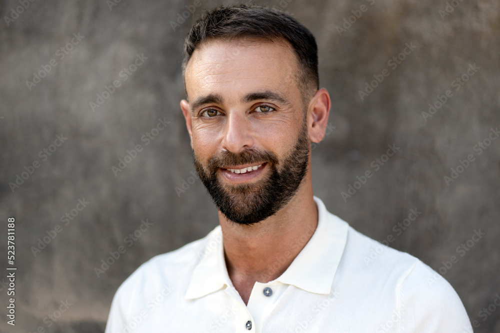 Portrait of handsome smiling latin man looking at camera isolated on grey background. Happy bearded customer after barbershop service Portrait of handsome smiling latin man looking at camera isolated on grey background. Happy bearded customer after barbershop service