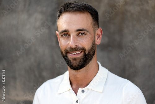 Portrait of handsome smiling latin man looking at camera isolated on grey background. Happy bearded customer after barbershop service 