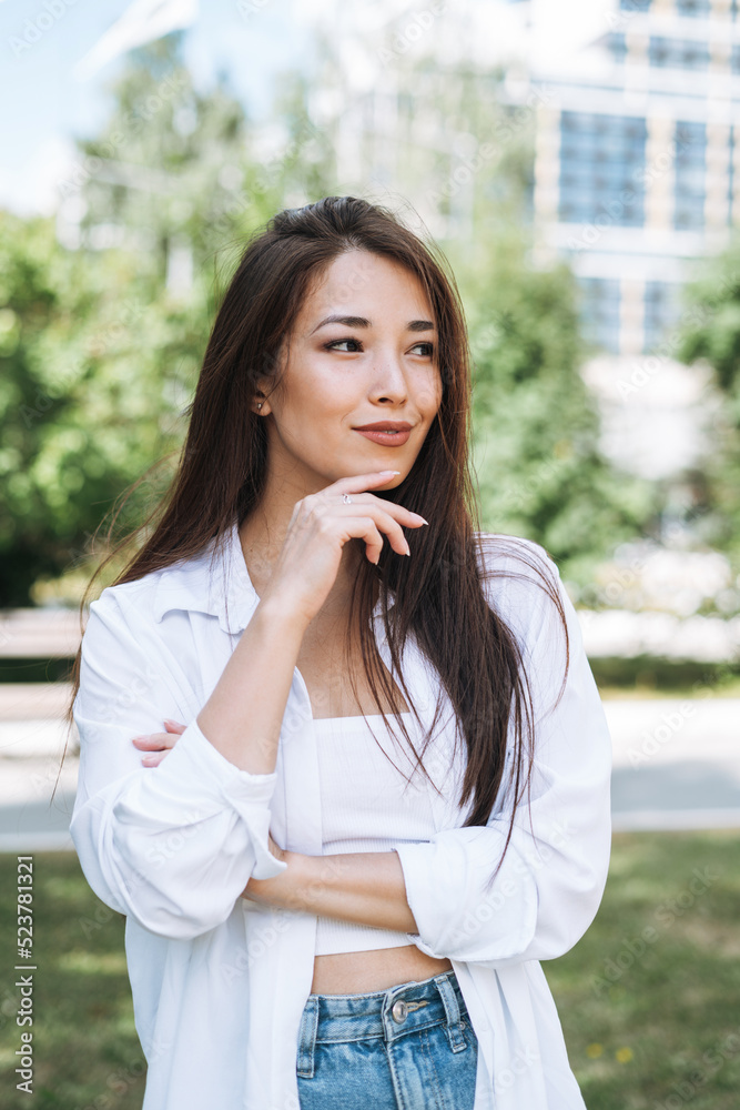 Fototapeta premium Portrait of young asian woman student with long hair in city park