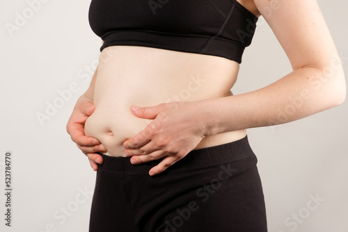 A woman shows an inflated thick belly, the concept of excess weight and weight loss.