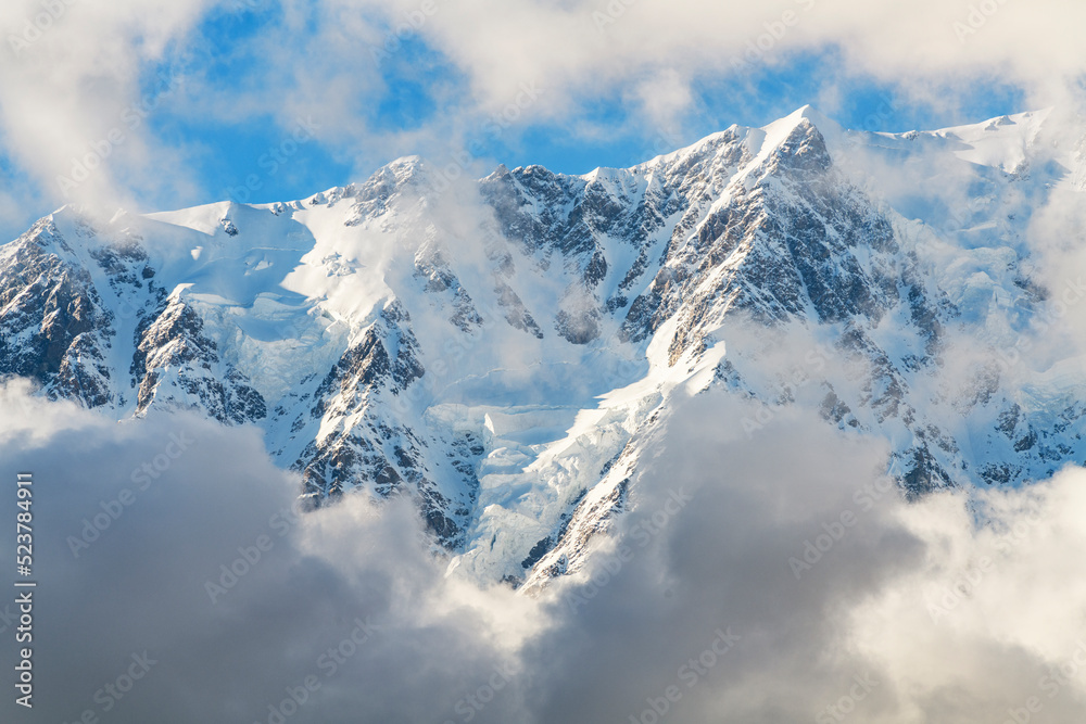 Clouds over the snow covered mountains. High mountains peak. Beautiful winter landscape.