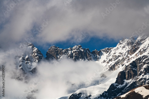 Clouds over the snow covered mountains. High mountains peak, winter landscape. © Inga Av