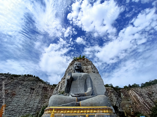 The landscape of monks carved on the cliff Wat Khao Tiam in Thailand, beautiful with clear sky, beautiful trees on the cliff, religious cultural attraction. photo