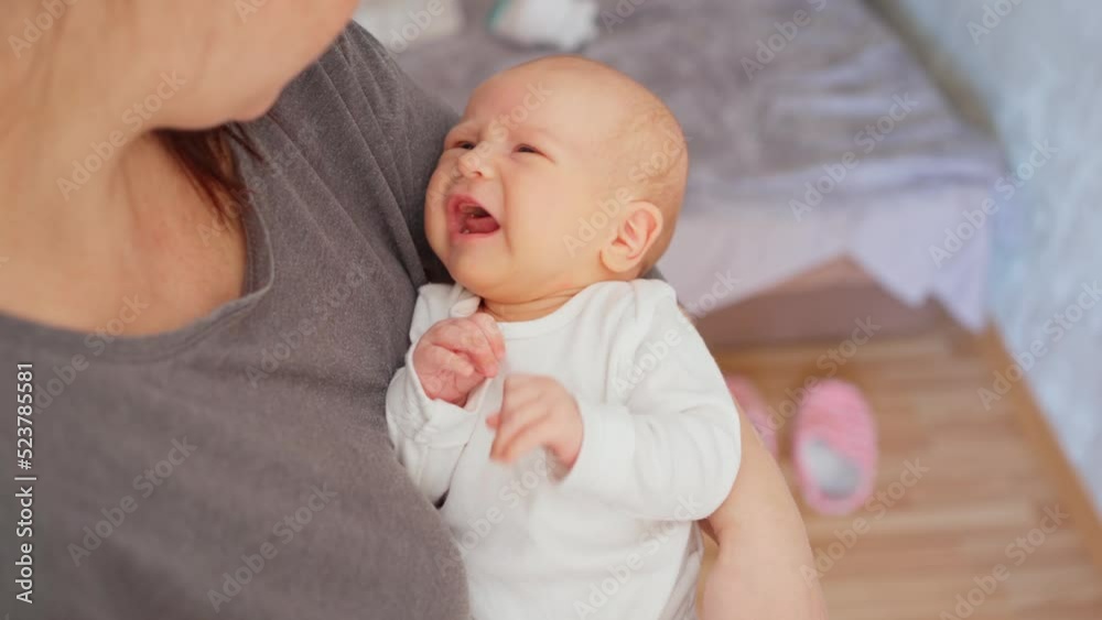 the baby lies in his mother's arms and cries. monthly baby. caring for a little baby the baby lies in his mother's arms and cries. monthly baby. caring for a little baby