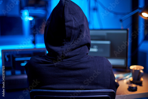 cybercrime, hacking and technology concept - close up of male hacker in dark room writing code or using computer virus program for cyber attack