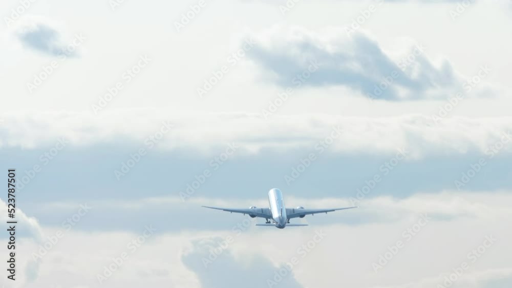 Jet unrecognizable plane takeoff and climb in cloudy sky, view from the back long shot. Tourism and travel concept Jet unrecognizable plane takeoff and climb in cloudy sky, view from the back long shot. Tourism and travel concept
