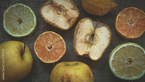 Still life of fruits, lemon, orange and apple, in the process of aging or rusting on a dark wooden table