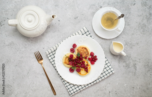 Hot cheesecakes with berries and green tea on concrete background ror breakfast. Top view.