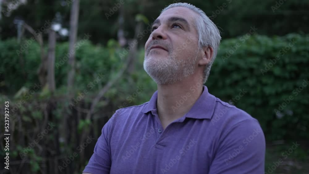 Meditative older man standing outside at park looking at sky in contemplation Meditative older man standing outside at park looking at sky in contemplation
