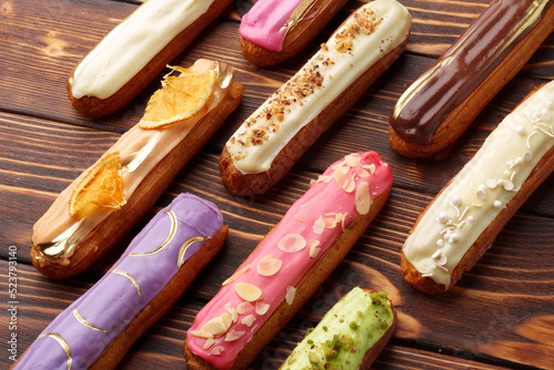 Fotografia Assortment of sweet and colorful eclairs on wooden background