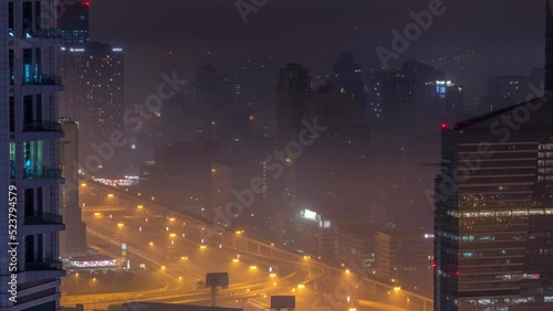 Dubai aerial view showing al barsha heights and greens district area during all night timelapse from Dubai marina. Illuminated towers and skyscrapers with traffic on a highway from above. Lights photo